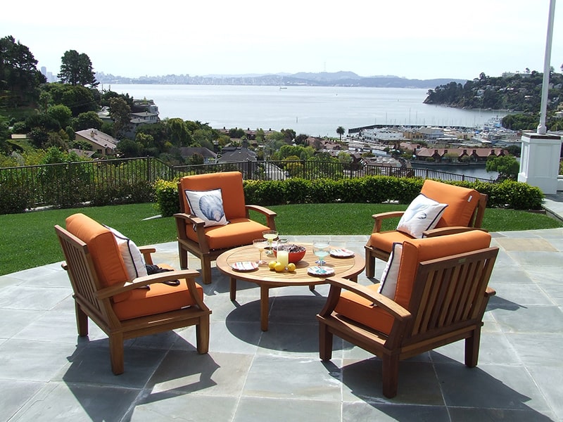 This is an image of a tile patio with orange patio furniture. LandTech Landscaping specializes in patio installation similar to the one shown here.