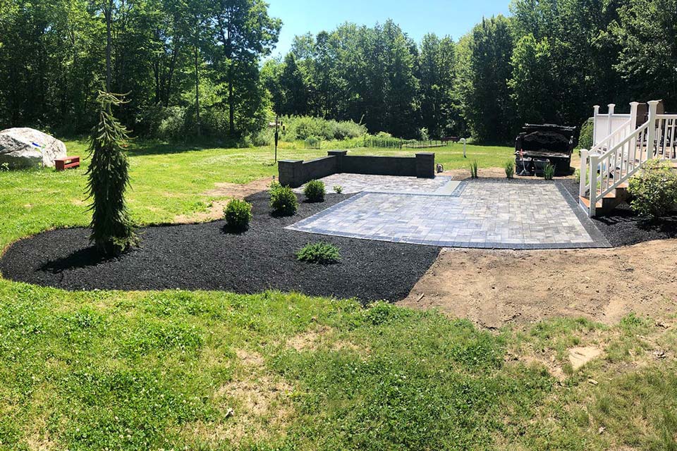 This is an image of a tile patio with orange patio furniture. LandTech Landscaping specializes in patio installation similar to the one shown here.